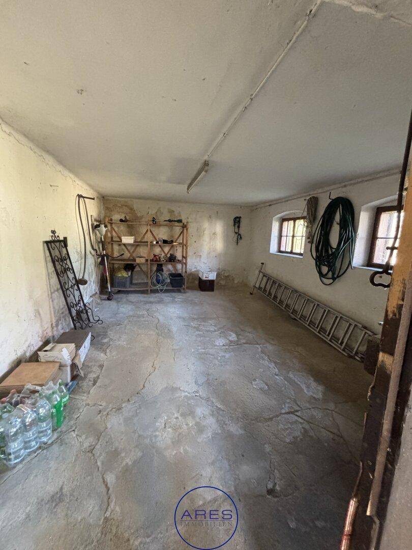 Geräumiger Abstellraum oder Werkstatt mit Betonboden und kleinen Fenstern.