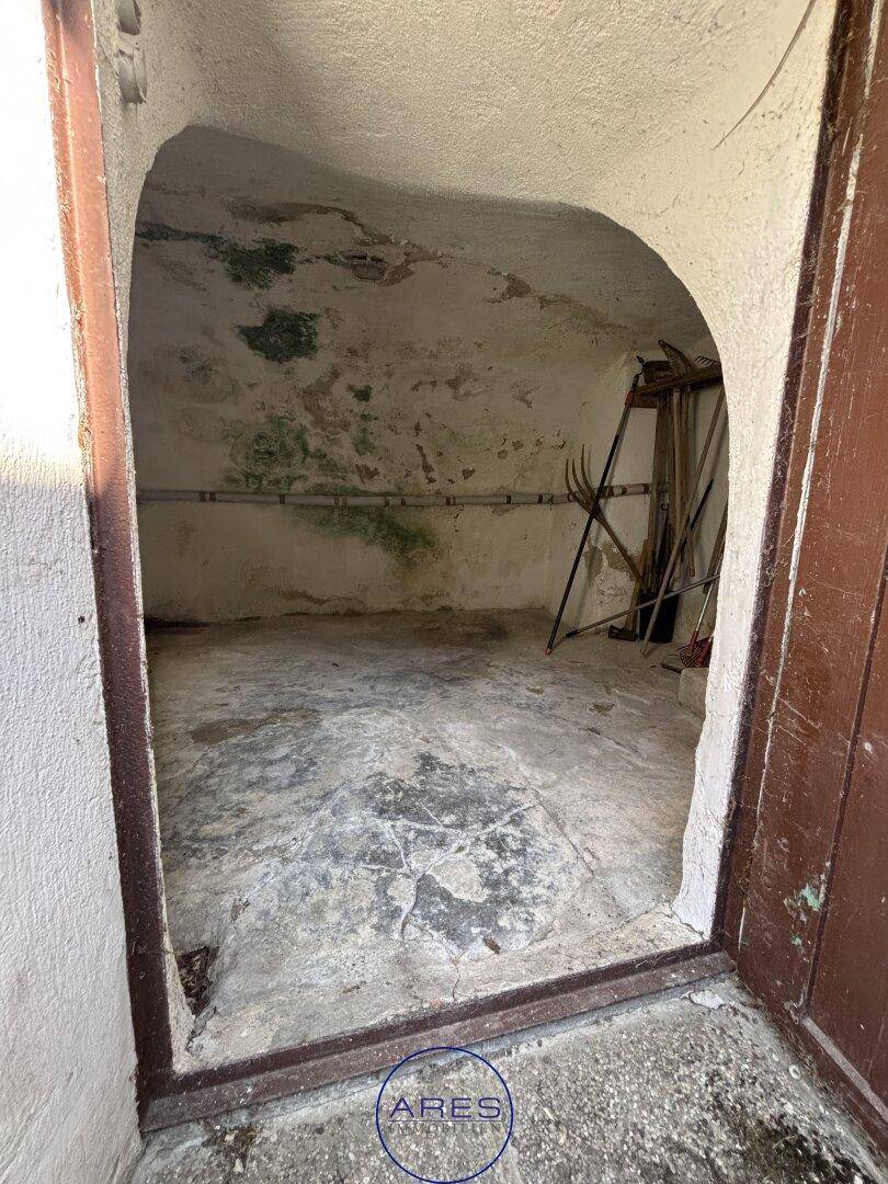 Kleiner, rustikaler Lagerraum oder Kellerzugang mit rauen Wänden und Betonboden.