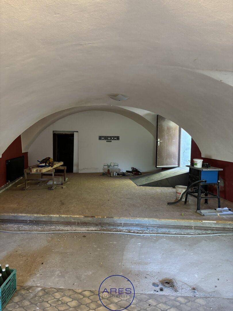 Weiterer Blick in den großen Raum mit Gewölbedecke und Zugang zu einem anderen Bereich.