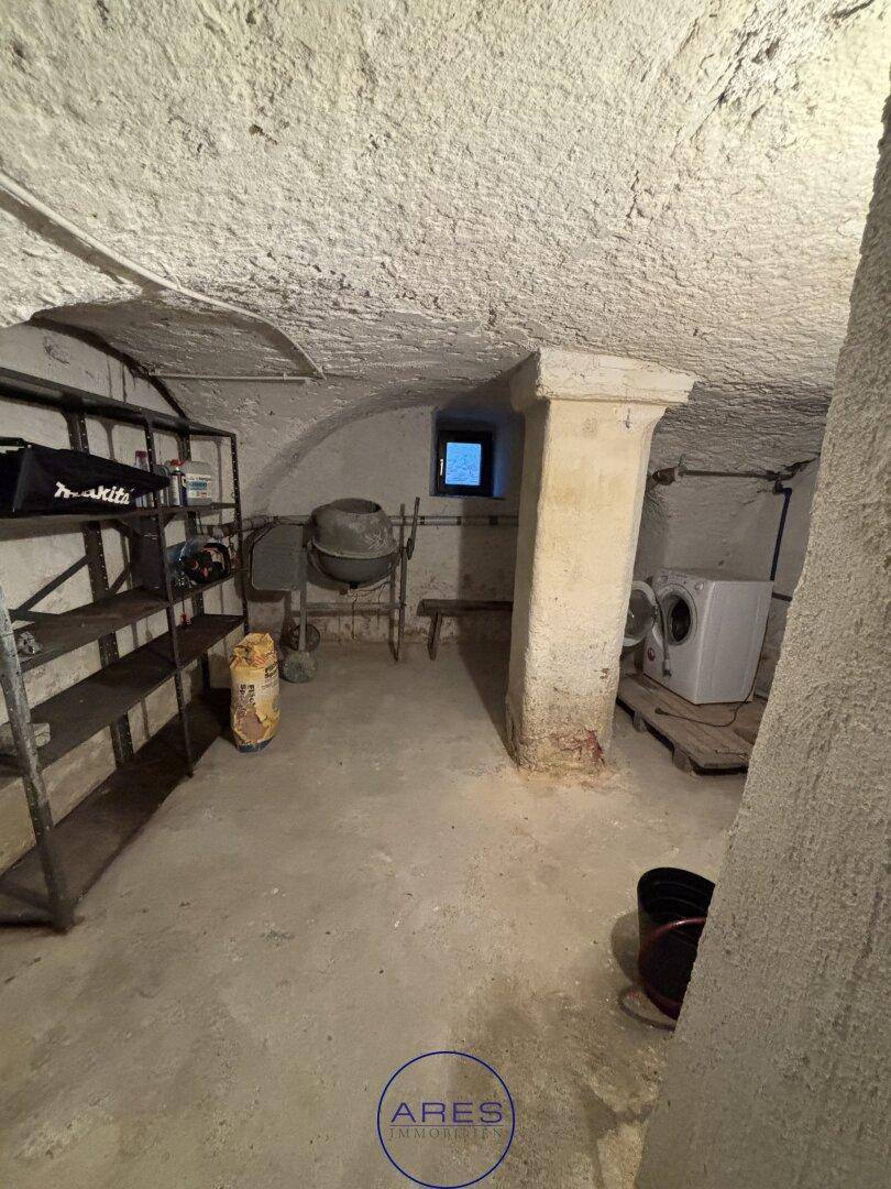 Kellerraum mit Betonboden, Regalen und Waschmaschine, ideal als Hauswirtschaftsraum.