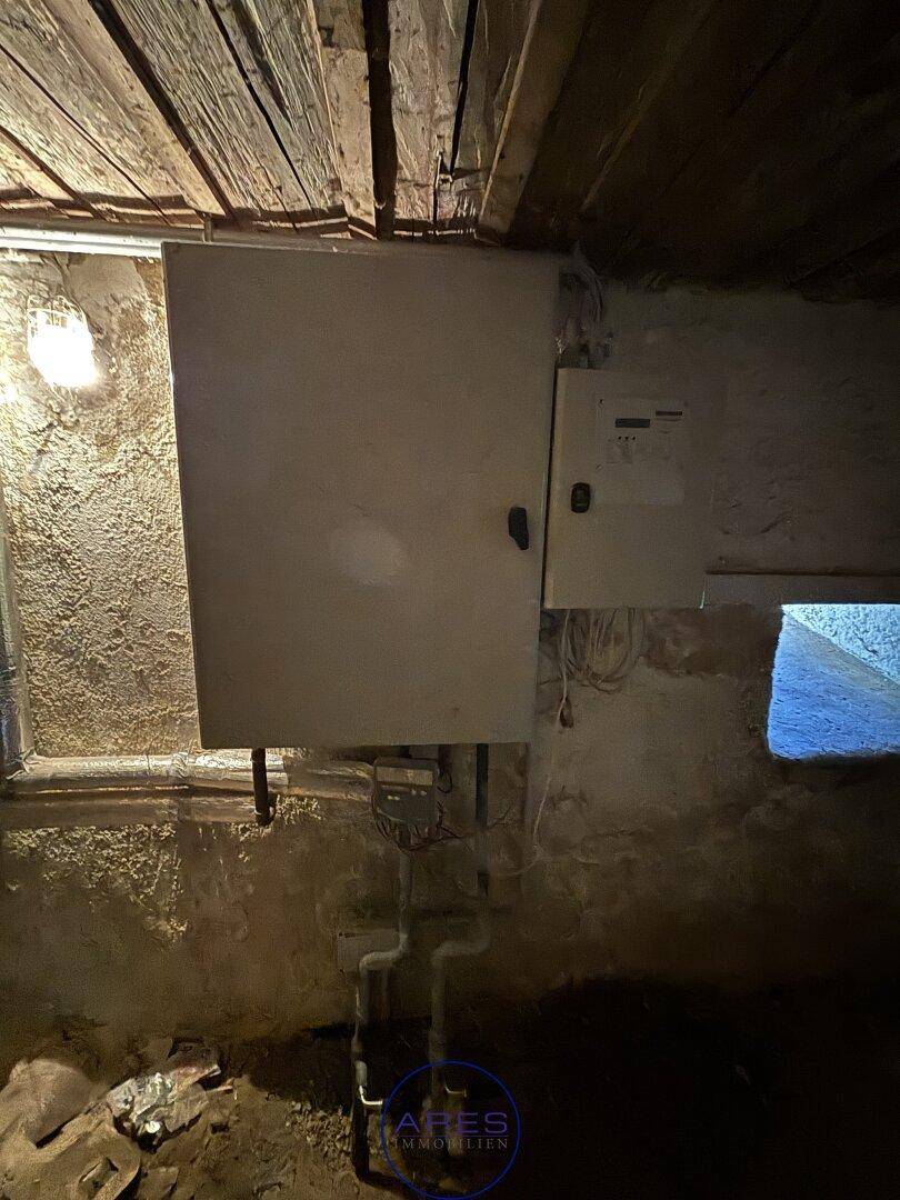 Kellerraum mit elektrischen Schaltkästen und sichtbaren Rohrleitungen.