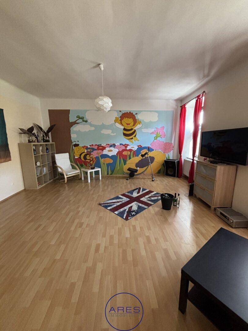 Helles Zimmer mit farbenfroher Wandmalerei und Laminatboden, ideal für Kinder.