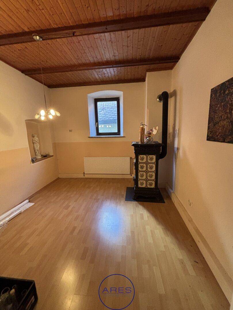 Rustikaler Raum mit Holzbalkendecke, Laminatboden und einem Holzofen.