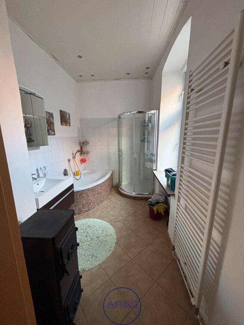 Badezimmer mit Eckdusche, Eckbadewanne, Waschbecken und beheiztem Handtuchhalter.