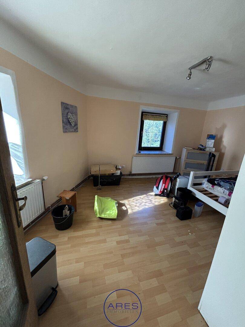 Schlafzimmer mit Laminatboden, einem Fenster und einfacher Möblierung.