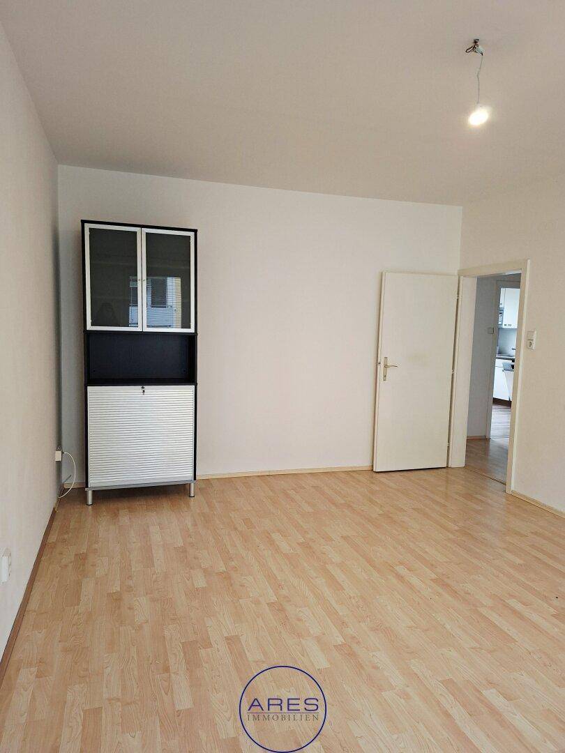 Geräumiges Wohnzimmer mit Laminatboden und weiß gestrichenen Wänden, bereit zur Einrichtung.