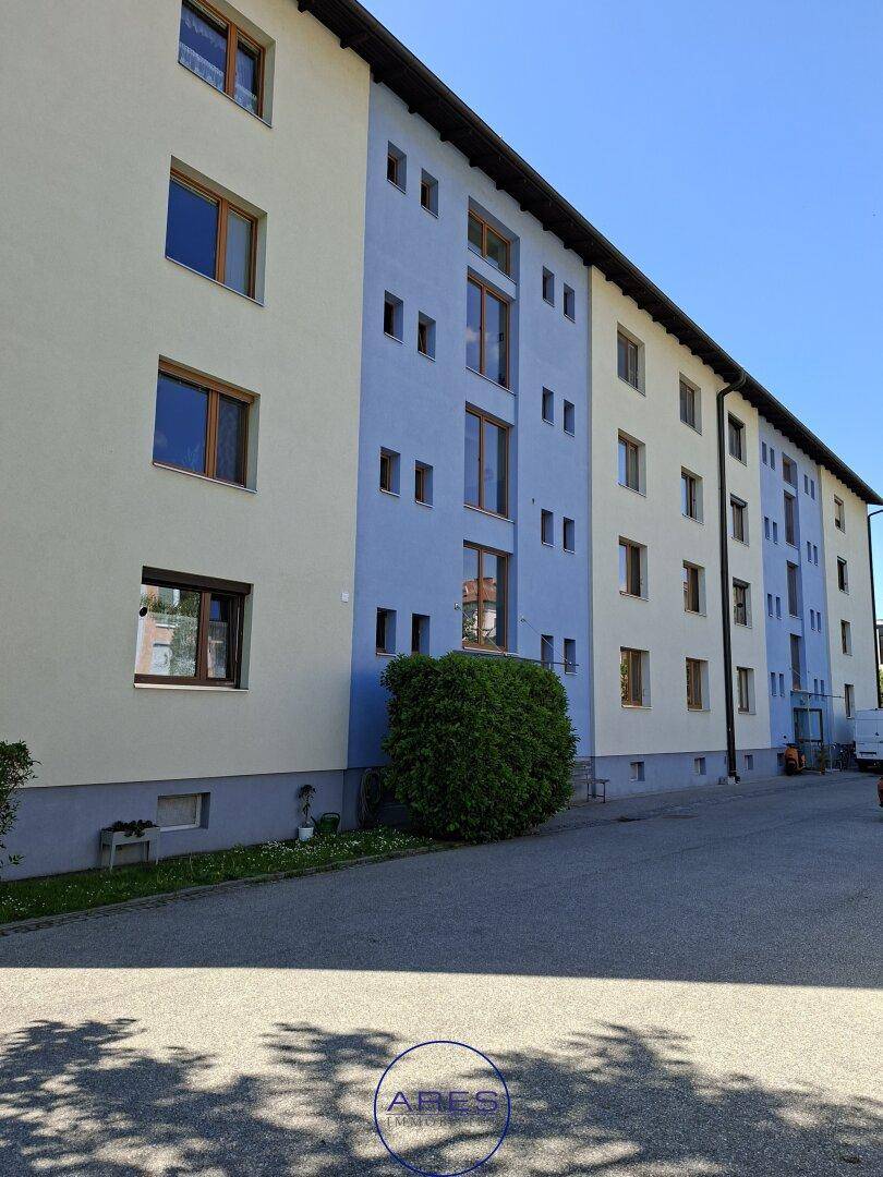 Mehrfamilienhaus mit blauer und beiger Fassade entlang einer ruhigen Wohnstraße.