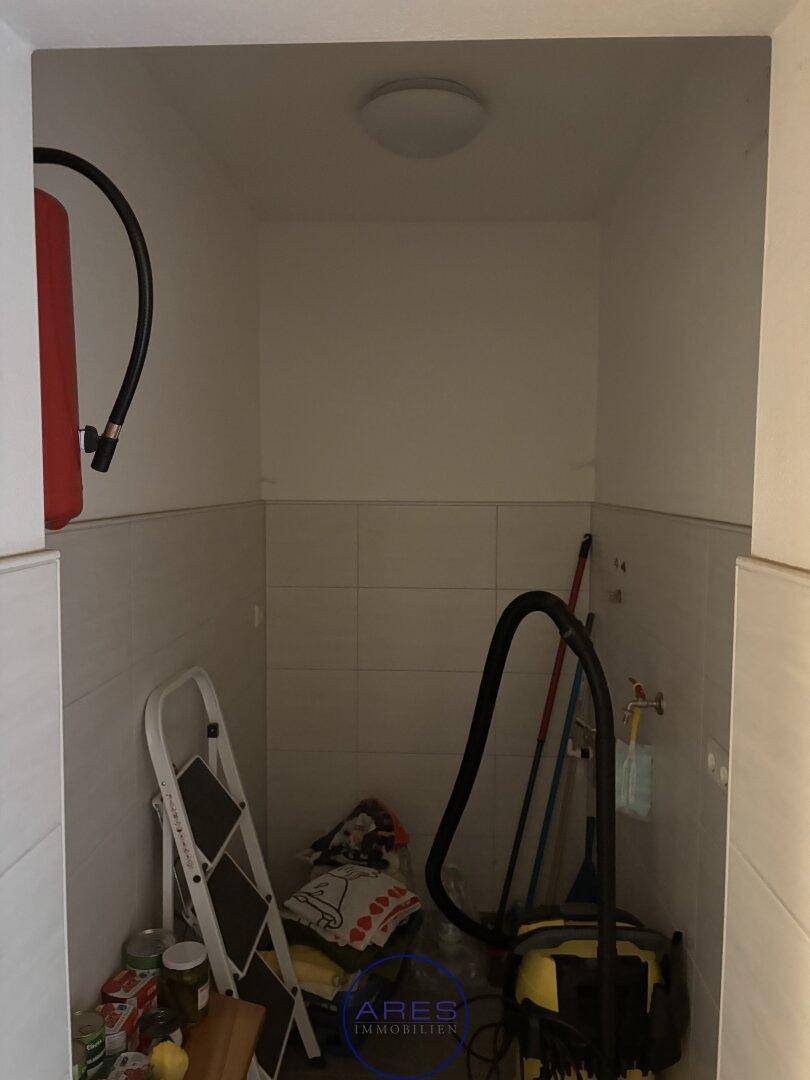 Kleiner Abstellraum mit Fliesenboden und einem Feuerlöscher an der Wand.