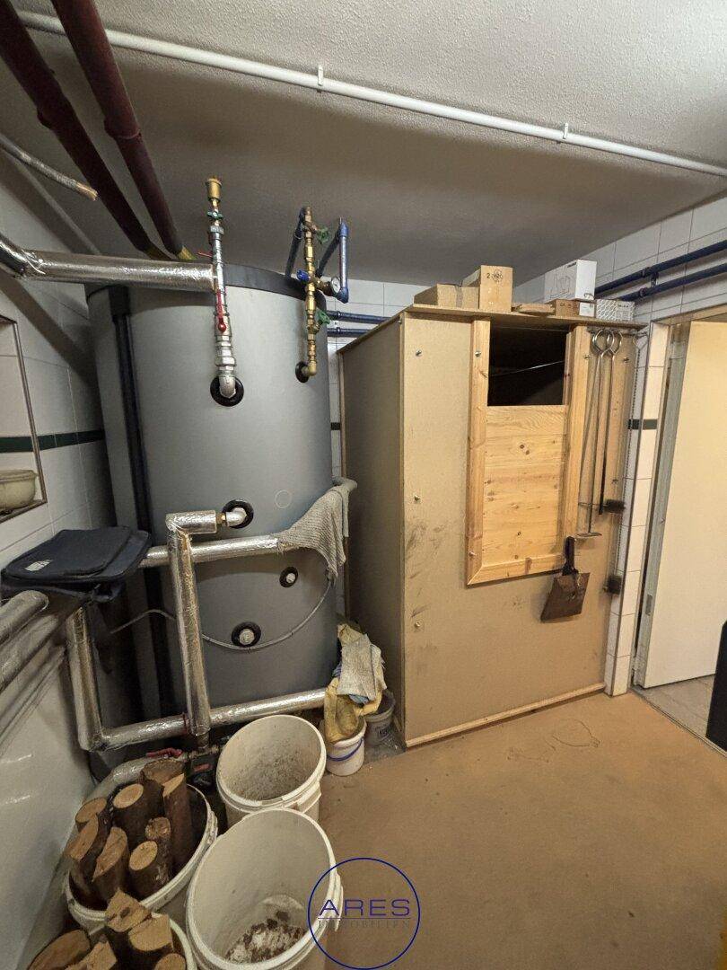 Heizungsraum mit Warmwasserspeicher und Holzpelletlager, bereit für den Winter.