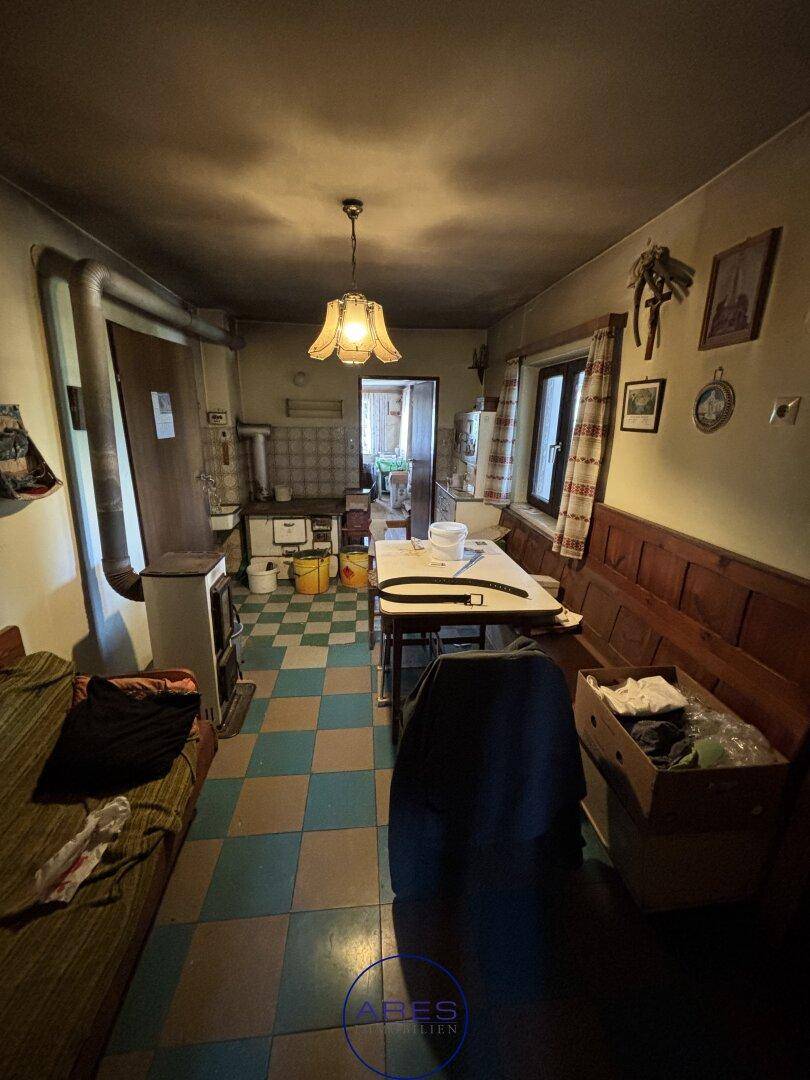 Traditionelle Küche mit kariertem Fliesenboden, Holzbank und einem alten Ofen.