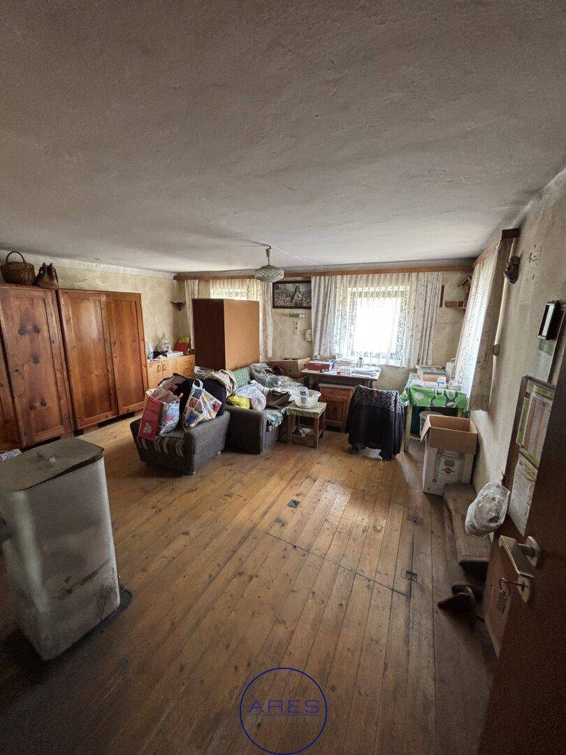 Geräumiges Wohnzimmer mit Holzdielenboden, traditionellen Holzmöbeln und Fensterblick.