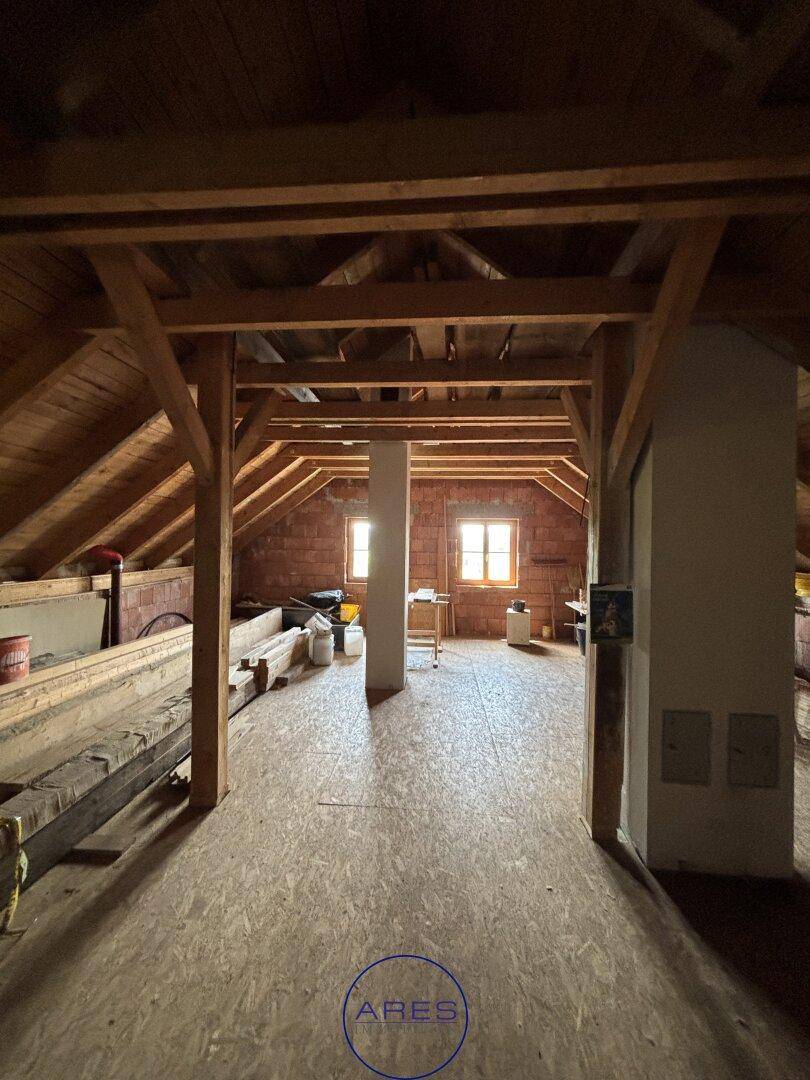 Heller Dachbodenbereich mit Holzbalken und Fenstern, ideal für einen zukünftigen Ausbau.