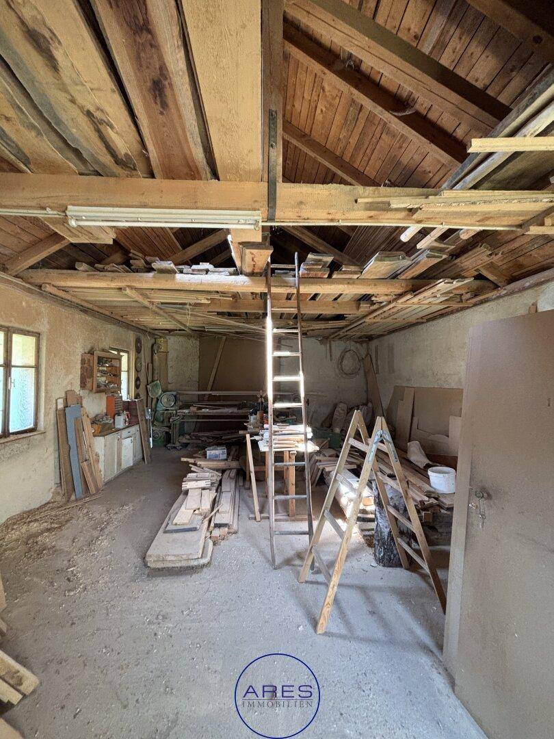 Werkstattraum mit Werkzeugen, Holzmaterialien und einer Leiter, ideal für handwerkliche Arbeiten.