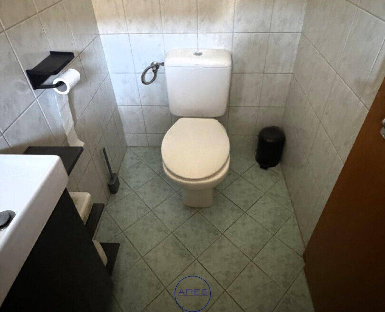 Kleines Gäste-WC mit WC, Waschbecken und hellen Fliesen.