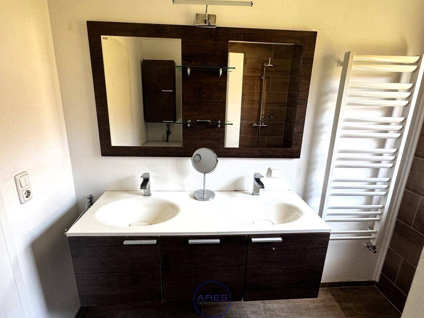 Modernes Badezimmer mit Doppelwaschbecken, großem Spiegel und beheiztem Handtuchhalter.