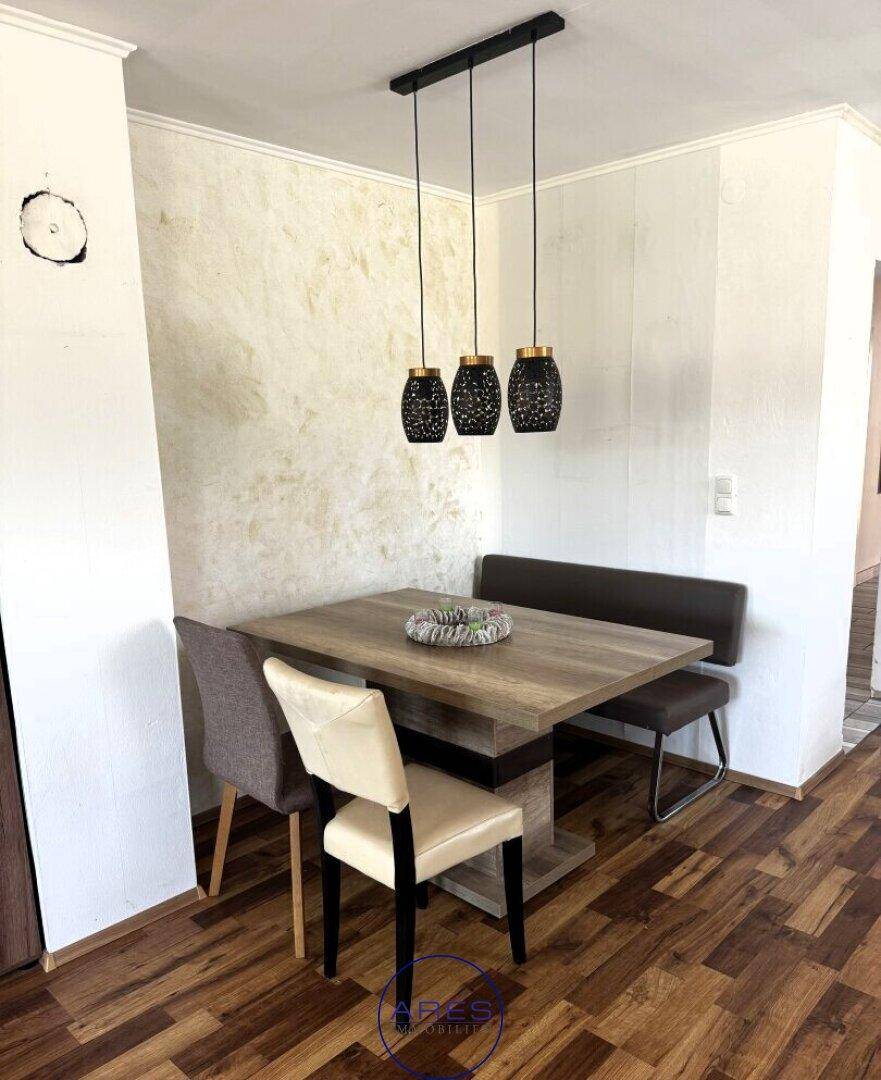 Gemütlicher Essbereich mit Holztisch, Sitzbank und modernen Hängelampen.