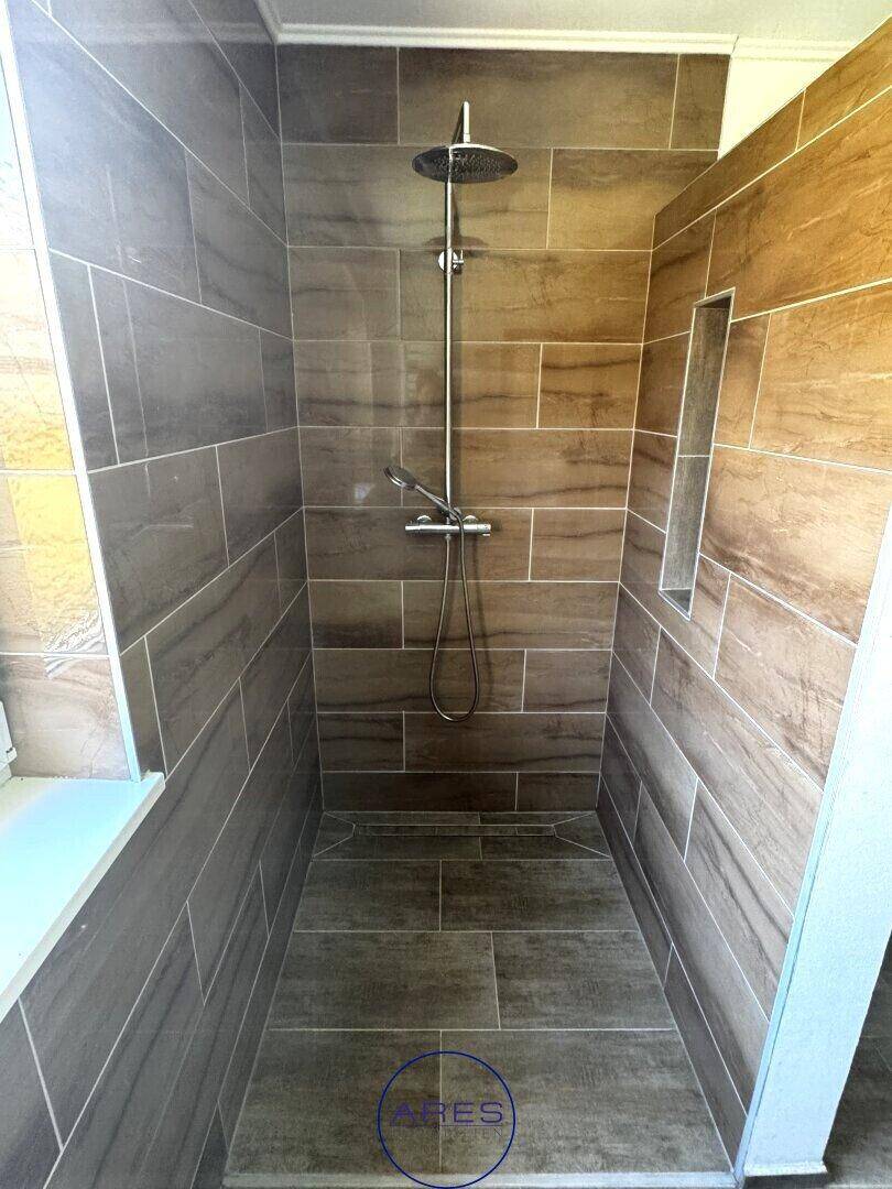 Geräumige begehbare Dusche mit Regenduschkopf und modernen Fliesen in Holzoptik.