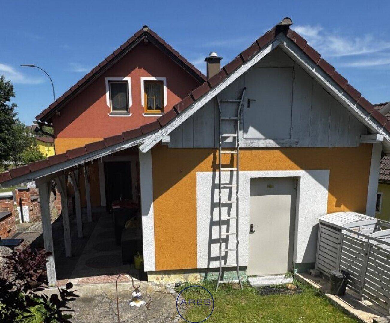 Seitenansicht des Hauses mit Anbau, Leiter und Außenbereich.