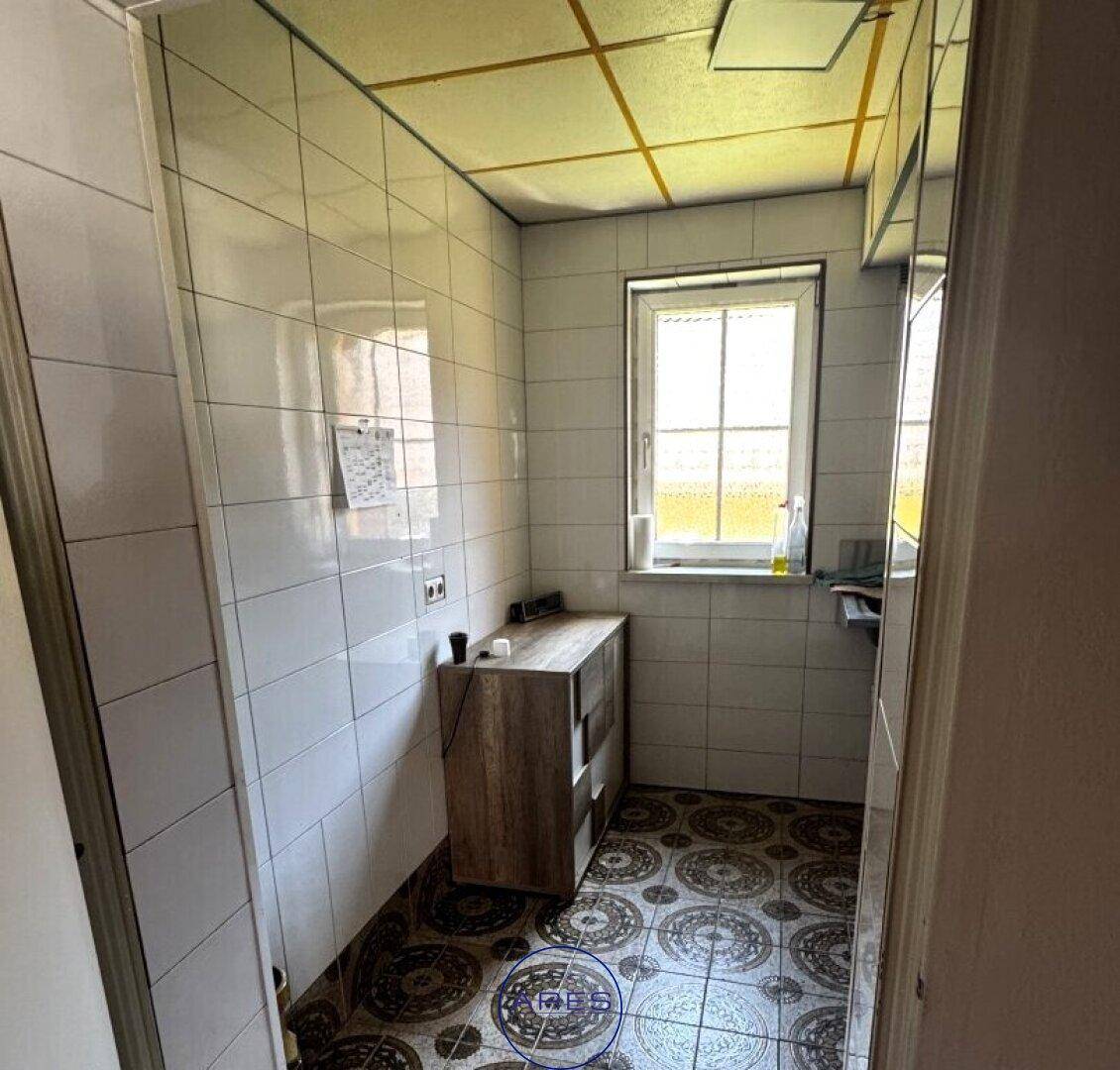 Hauswirtschaftsraum mit Fliesenboden, Fenster und Waschbecken.