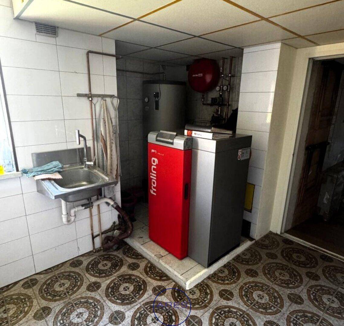 Heizungsraum mit moderner Heizungsanlage, Waschbecken und Fliesenboden.