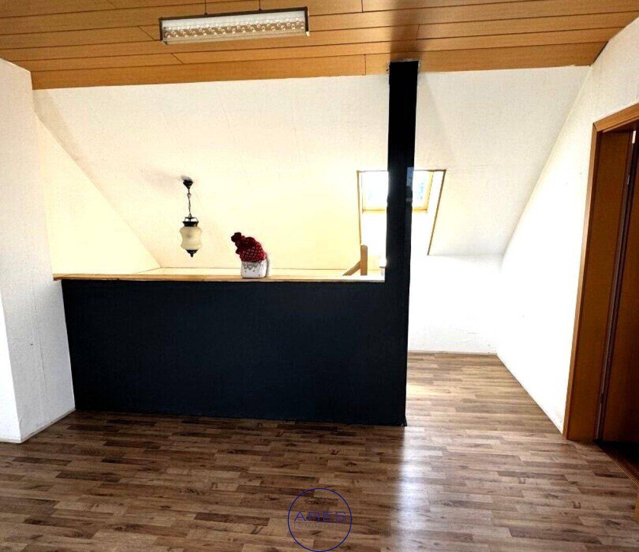 Offener Dachbodenbereich mit Holzbalkendecke und Laminatboden, ideal als zusätzlicher Wohnraum.