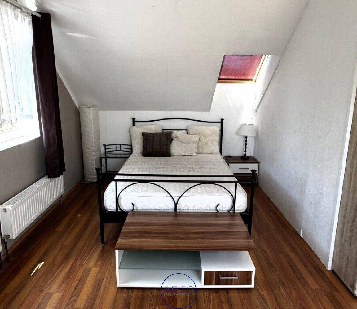 Gemütliches Schlafzimmer im Dachgeschoss mit Laminatboden, Bett und Dachfenster.