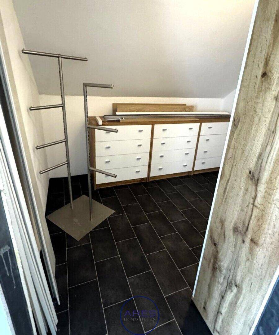 Praktischer Abstellraum im Dachgeschoss mit Regalen und dunklen Fliesen.