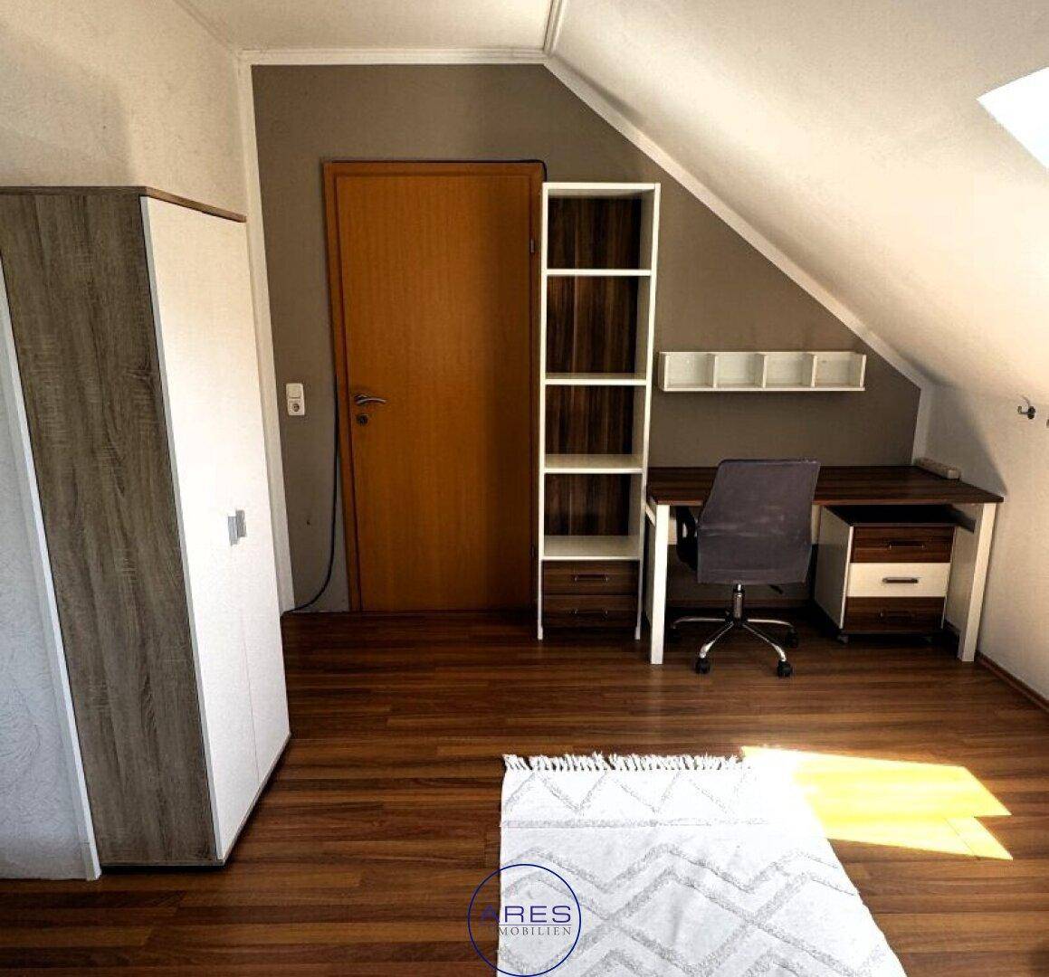 Arbeitszimmer im Dachgeschoss mit Laminatboden, Schreibtisch und Schrank.