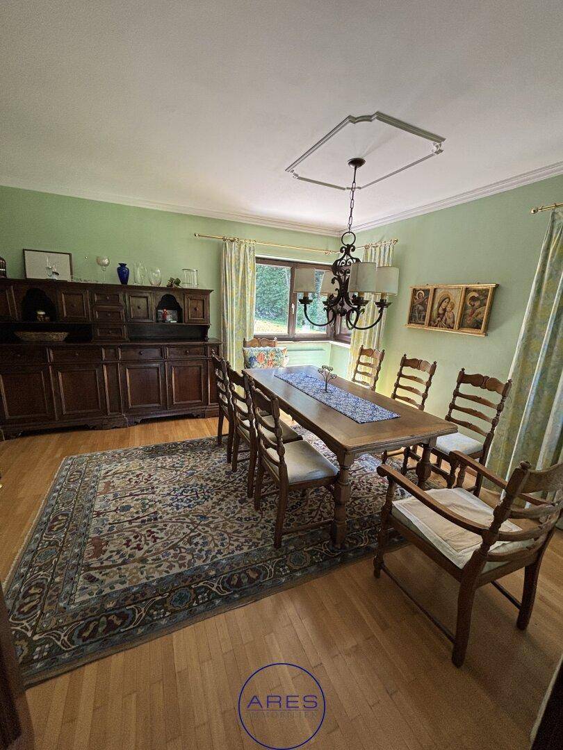 Traditioneller Essbereich mit Holztisch, Stühlen, grün gestrichenen Wänden und Parkettboden.