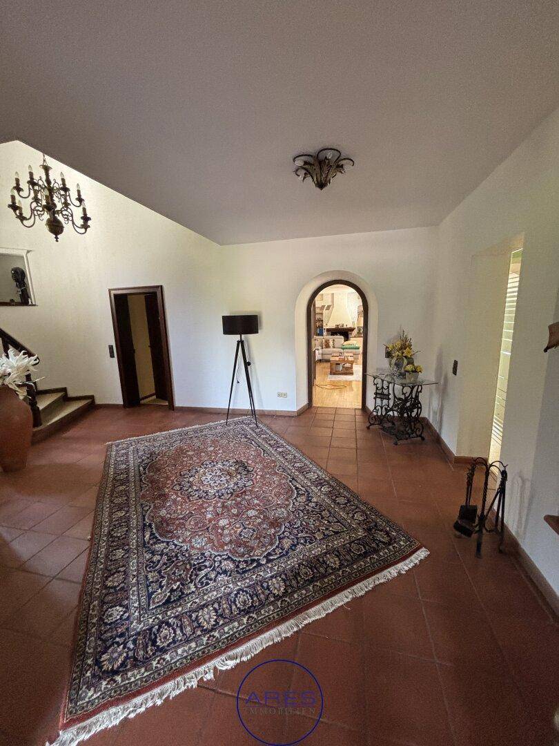 Heller Eingangsbereich mit Terrakottafliesen, Teppich und Blick in den Wohnbereich.
