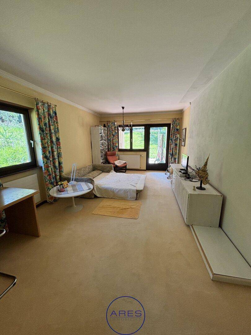 Helles Wohnzimmer mit Teppichboden, Schlafsofa und Zugang zum Außenbereich.