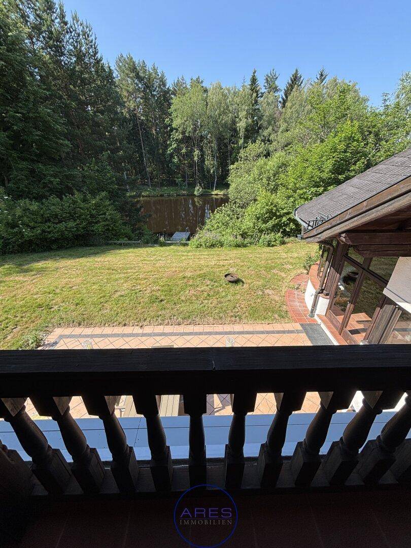 Großer Garten mit Rasenfläche, Bäumen und Blick auf die Natur.