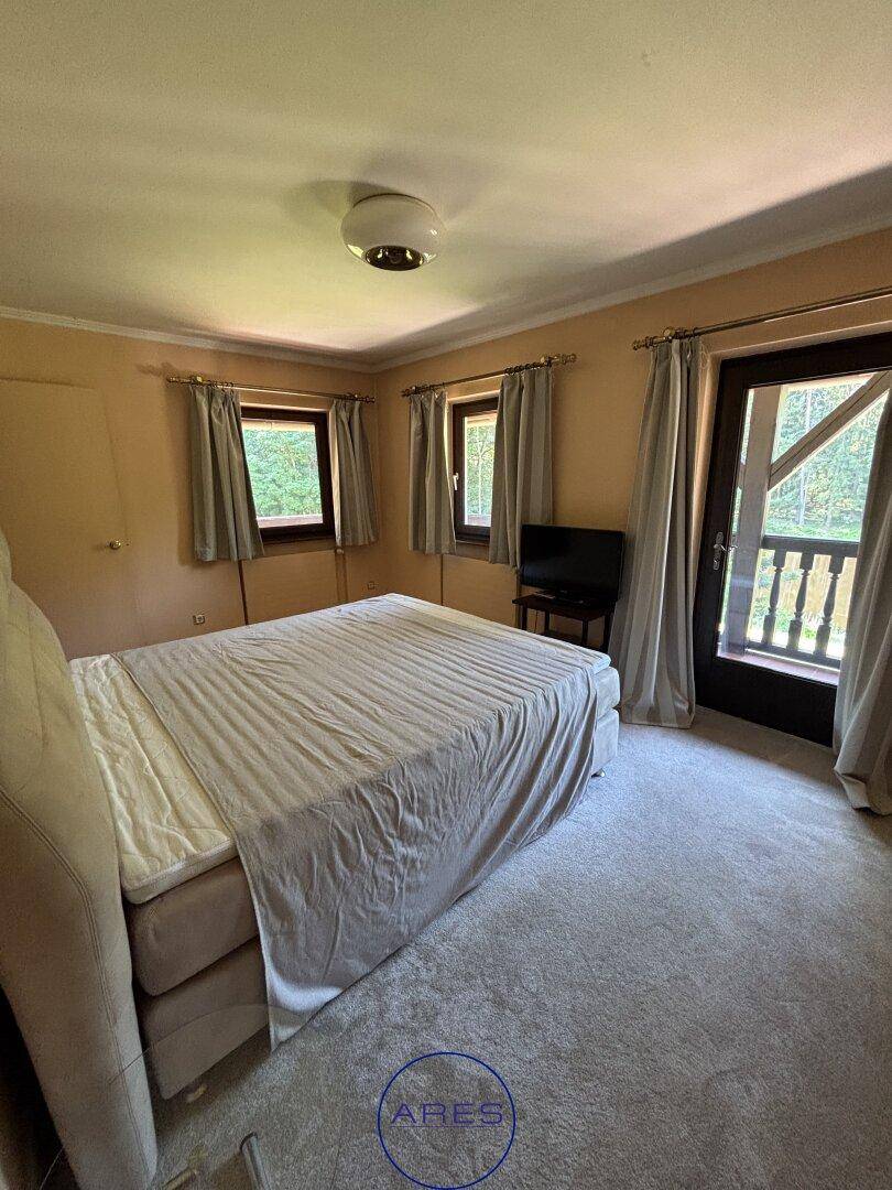 Schlafzimmer mit Teppichboden, Doppelbett und Zugang zum Balkon.