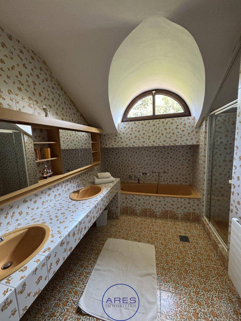 Badezimmer im 80er-Jahre-Stil mit Doppelwaschbecken, Badewanne und Dusche.