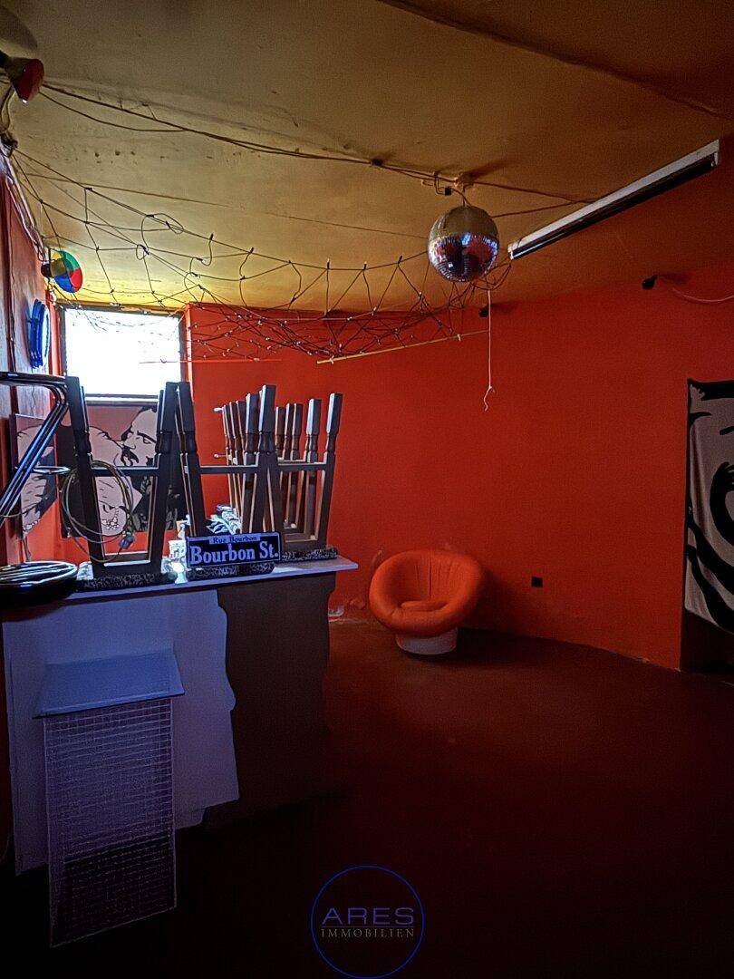 Raum mit orangefarbenen Wänden, einer Discokugel und einer Bar, möglicherweise ein Partyraum.