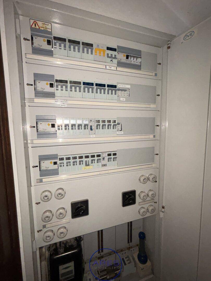Offener Sicherungskasten mit zahlreichen Schaltern und Sicherungen für die Stromversorgung.