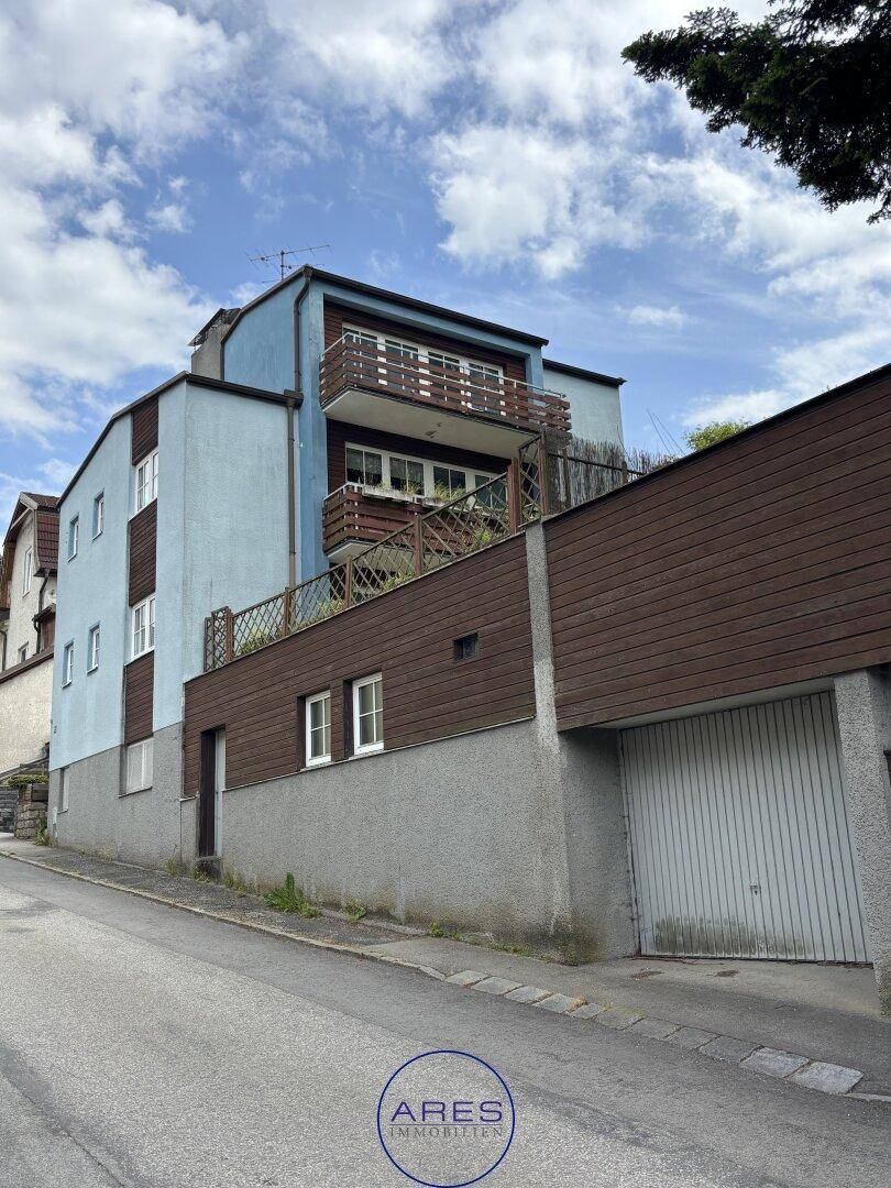 Rückansicht des Hauses mit mehreren Balkonen und einer integrierten Garage im Untergeschoss.