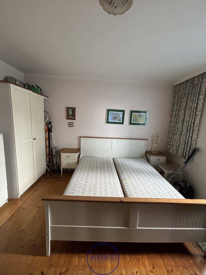 Schlafzimmer mit Doppelbett, Holzfußboden und einem großen weißen Kleiderschrank.