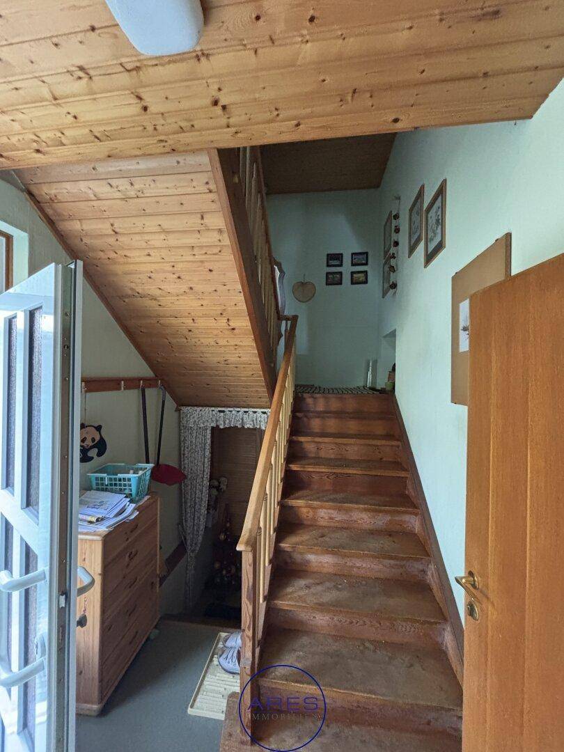 Treppenhaus mit Holzstufen und Holzdecke, das zu den oberen Etagen führt.