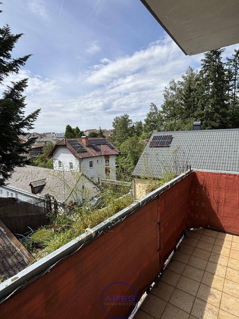 Balkon mit Fliesenboden und Blick auf die umliegenden Häuser und grüne Landschaft.