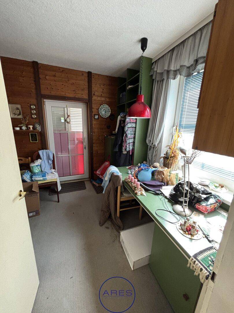 Zimmer mit Holzvertäfelung, Schreibtisch und Zugang zu einem Außenbereich.