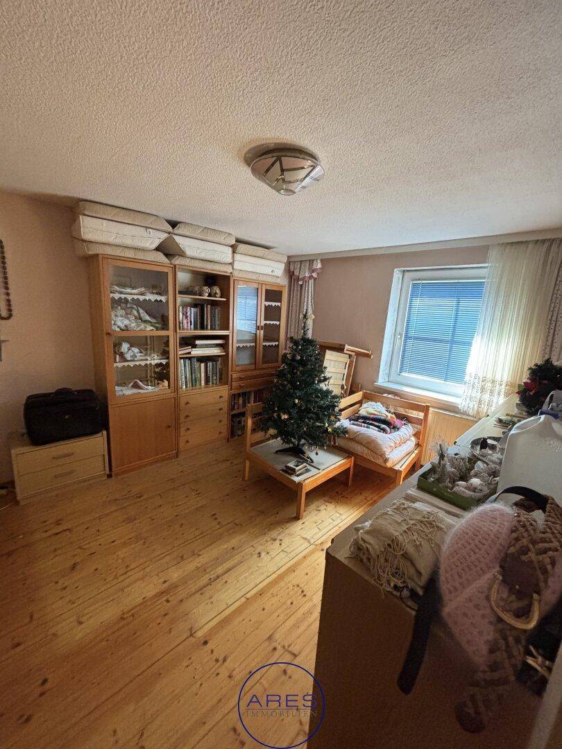 Geräumiges Zimmer mit Holzfußboden, Bücherregalen und einem Fenster.