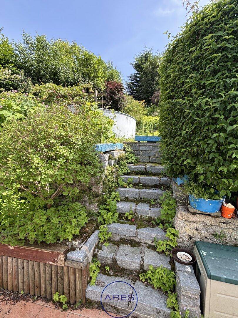Steintreppe führt durch einen üppigen Garten mit verschiedenen Pflanzen und einem kleinen Wasserbecken.