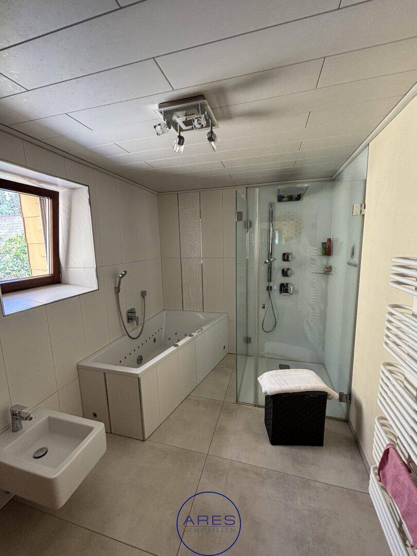 Modernes Badezimmer mit Whirlpool-Badewanne, Glasdusche und Fenster.