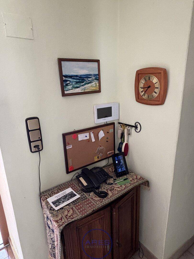 Detailansicht eines Flurbereichs mit Telefon, Pinnwand und Wanddekoration.