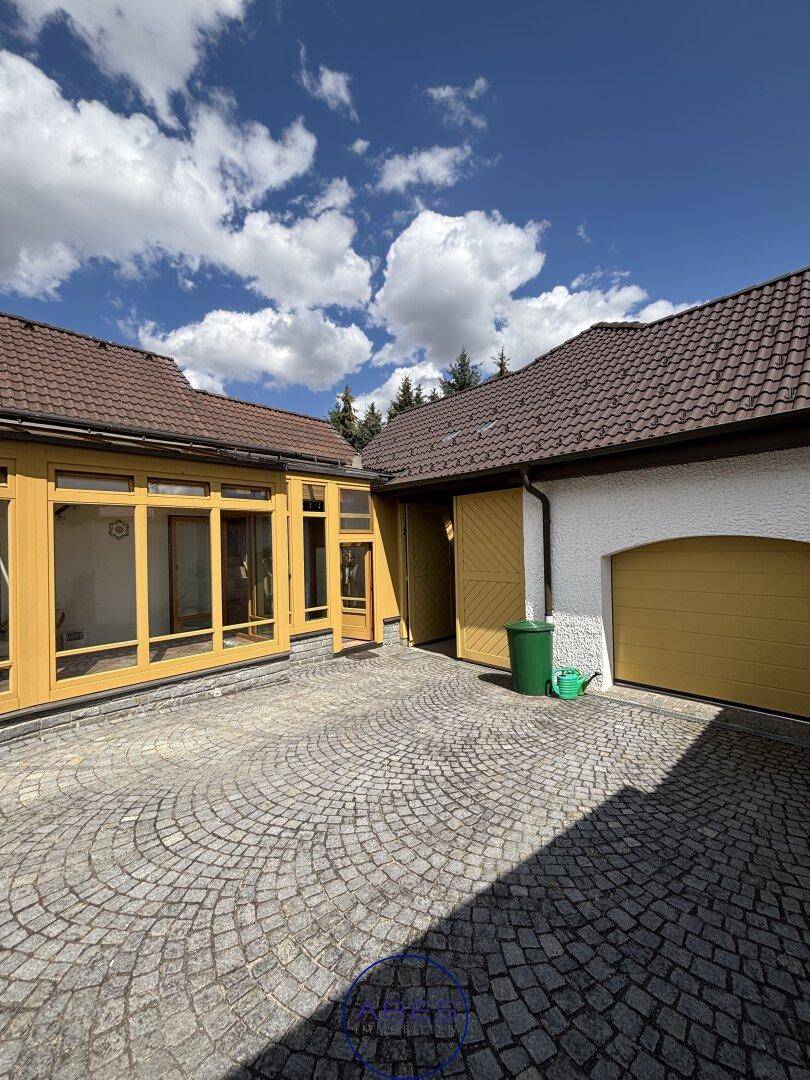 Sonniger Innenhof mit Kopfsteinpflaster und Gebäuden mit gelben Garagentoren.