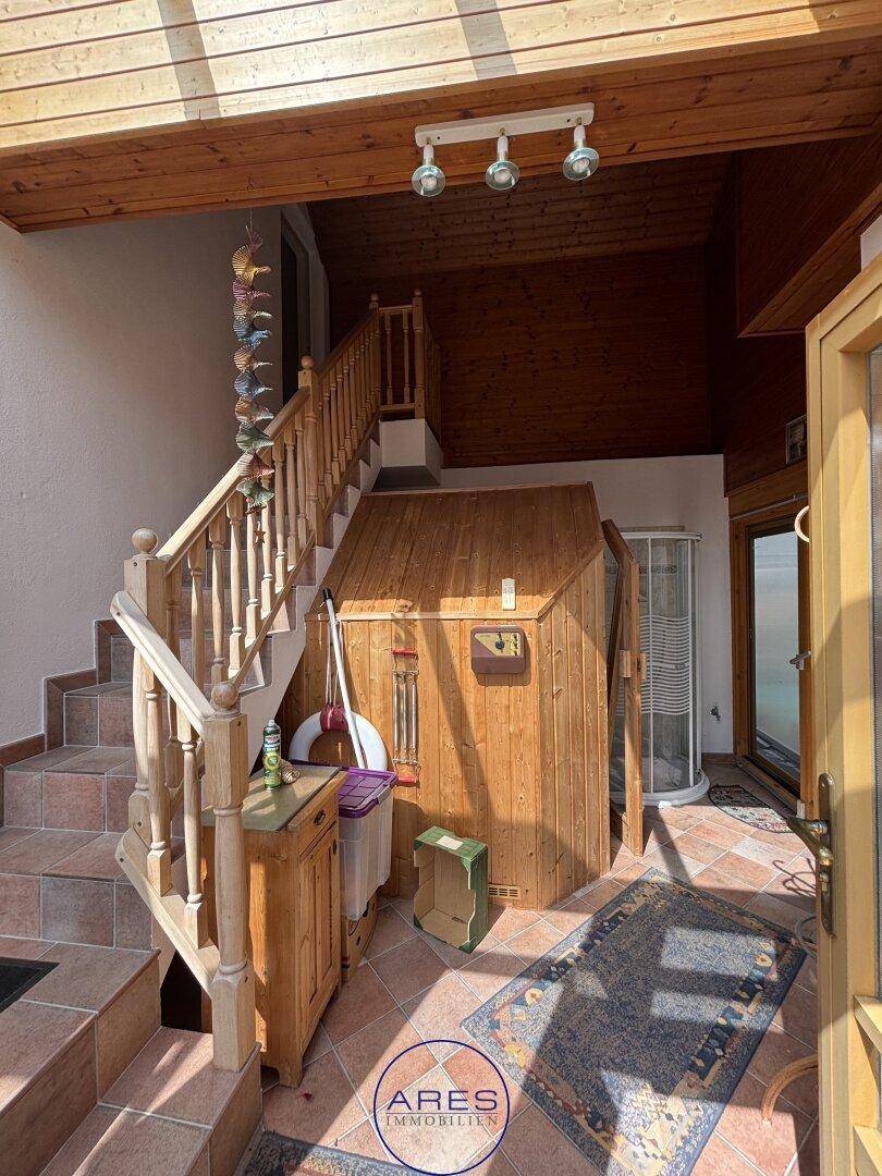 Eingangsbereich mit Holztreppe, Fliesenboden und integrierter Sauna.