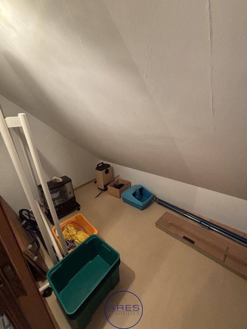 Abstellraum im Dachgeschoss mit schrägen Wänden und verschiedenen Gegenständen.
