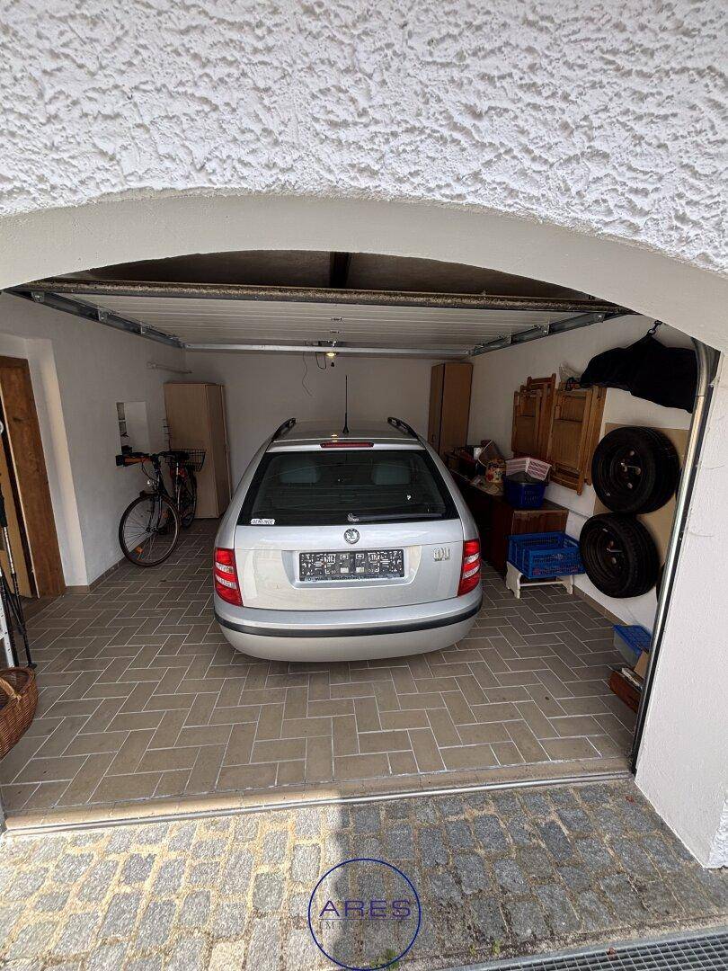 Garage mit gefliestem Boden und einem geparkten Auto.
