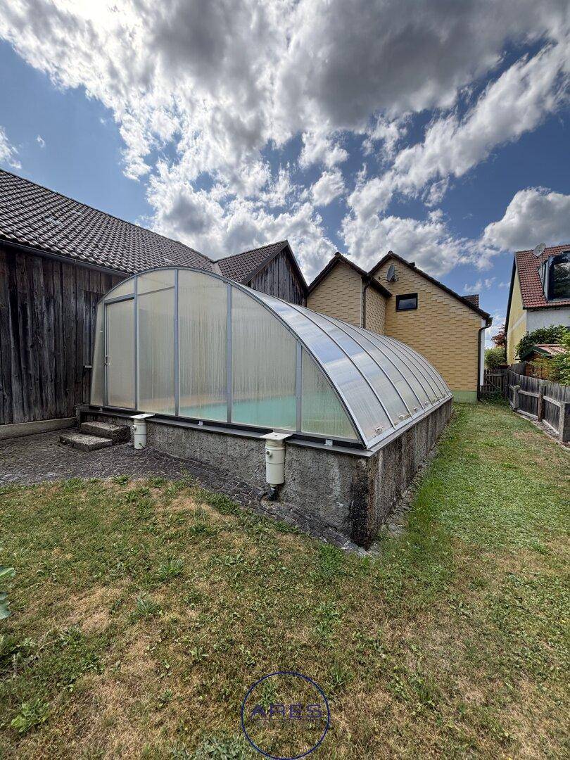 Überdachter Pool im Gartenbereich mit angrenzender Scheune.